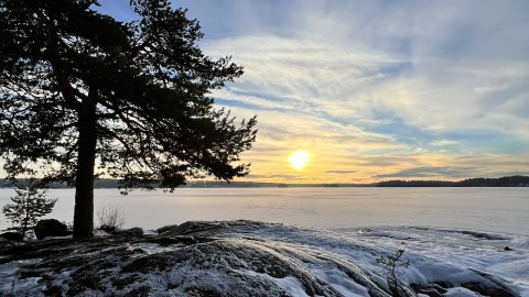 Talvinen auringonlasku järven rannalla