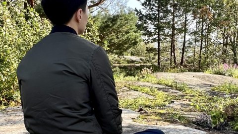 Mies istuu kalliolla metsäkylvyssä