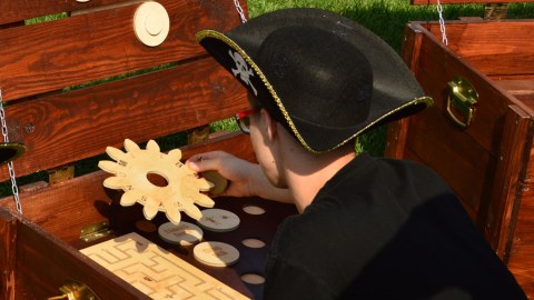 A person with the pirate hat solving a puzzle in an escape game.