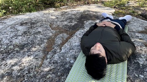 Mies meditoi makuualustan päällä metsäkylvyssä