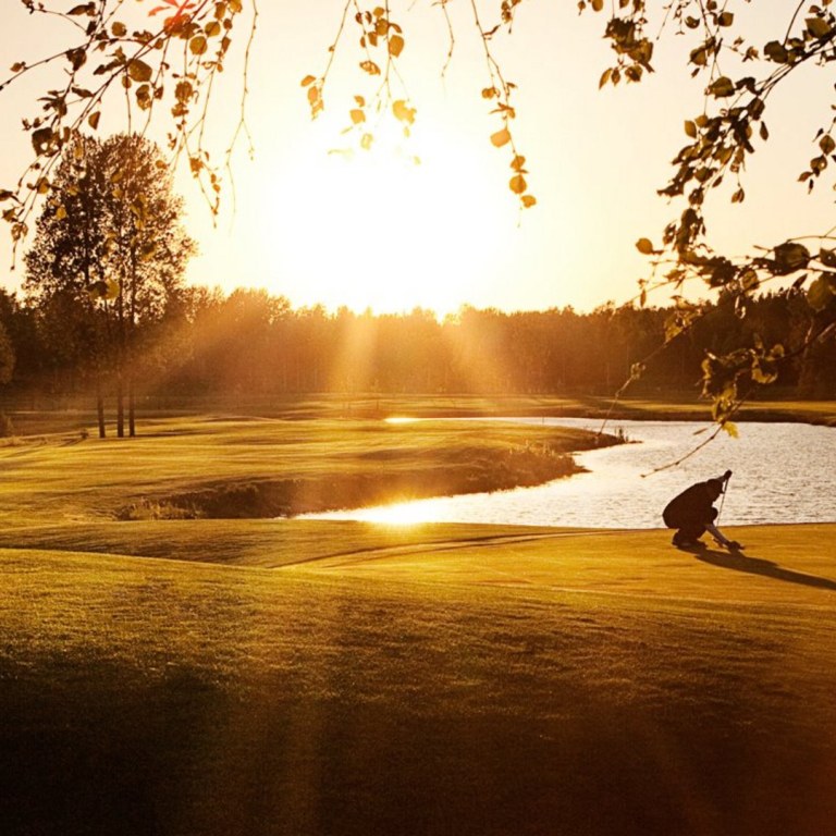 Ilta-auringossa kylpevä Hirsalan golfkenttä.
