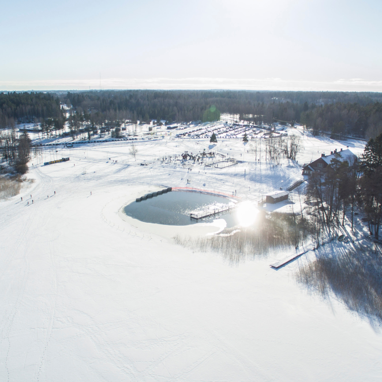 Dron view over Oittaa Recreational area covered in snow and people enjoying winter activities such as cross-country skiing