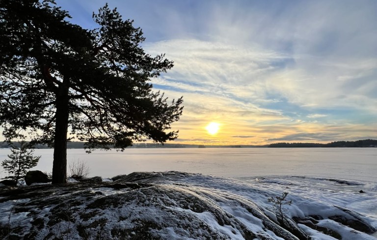 Talvinen auringonlasku järven rannalla