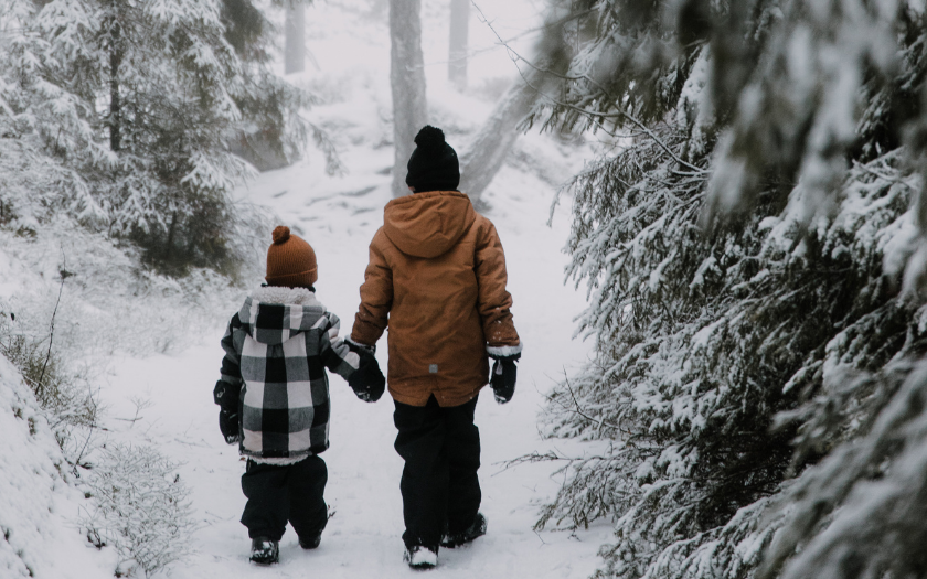 Two children walking in snowy forest