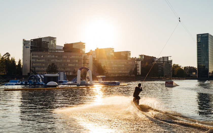 Person wakeboarding during golden hour. There are higher office buildings in the background.