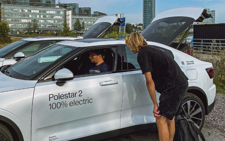 Person sitting in electric car and person giving him instructions