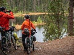 Two cyclists along the lake in forest 
