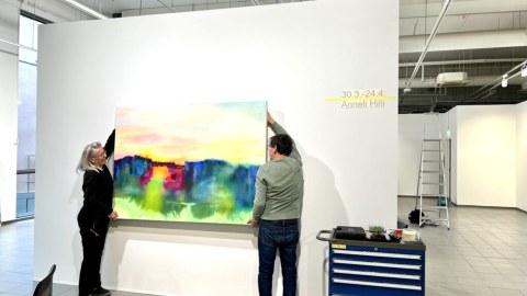 New art exhibitions every four weeks, artist Anneli Hilli lifting her painting on the wall.