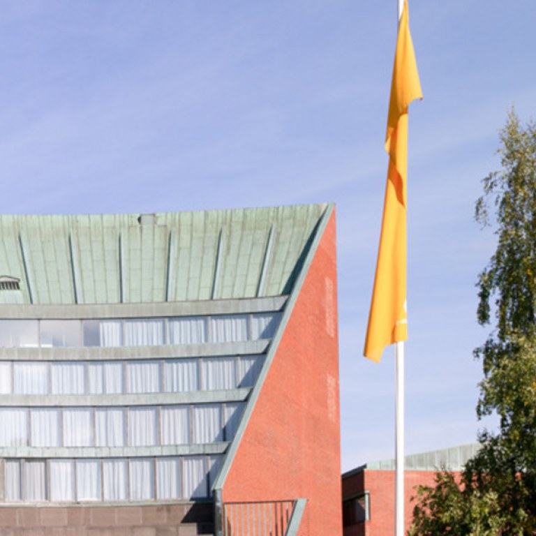 Aalto-yliopiston Kandidaattikeskus ulkoapäin kesämaisemassa.