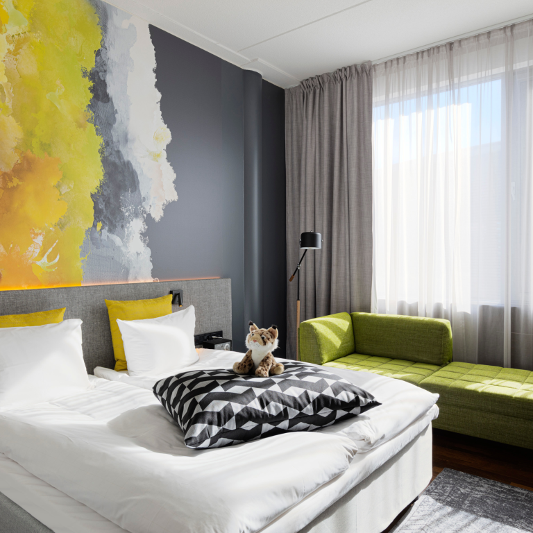 Hotel room at Glo Hotel Sello with art on the wall and comfy looking bed with fluffy toy for children