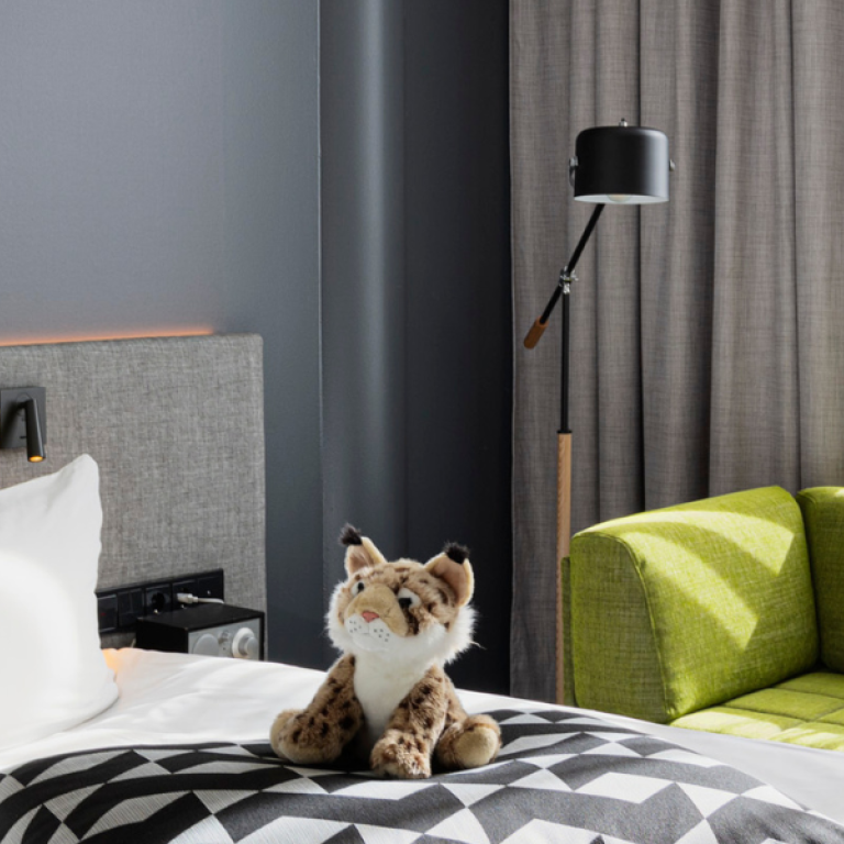 Soft toy animal sitting on hotel's bed in Glo Hotel Sello