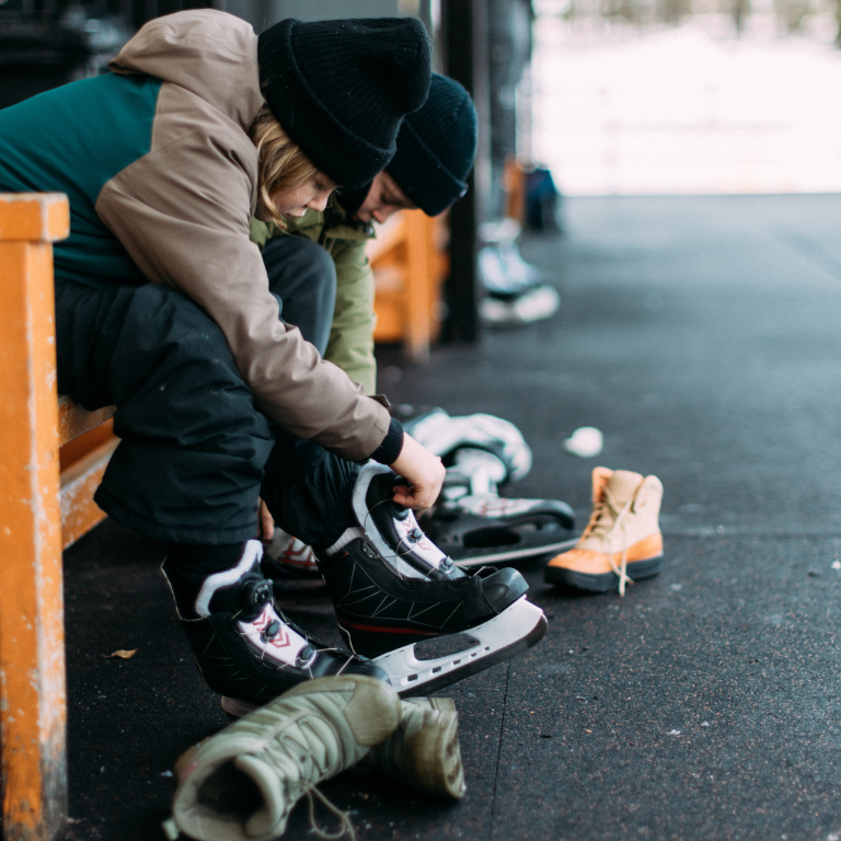 Children putting on ice skates outdoors