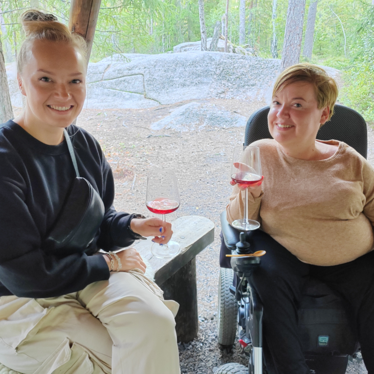 Two women enjoying red wine testing in the forest