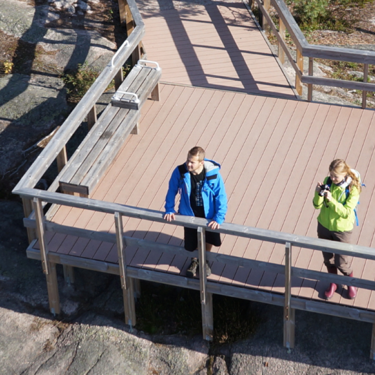 People enjoying viewpoint in Nuuksio National Park and logo of 30 years old national park