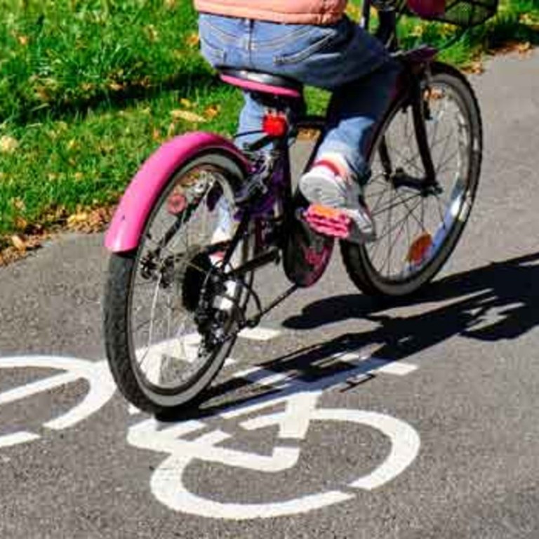 Kuva lapsen pyörästä ja alavartalosta, kun lapsi pyöräilee kevyen liikenteen väylällä.