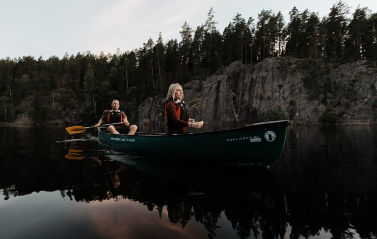 A man and a woman canoeing in the Nuuksio Hawk Lake