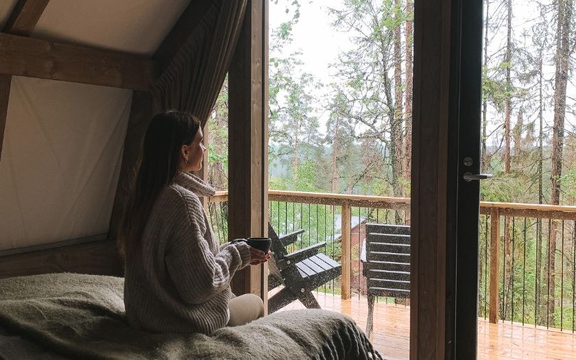 Woman with a cup of tea sitting in glamping nest