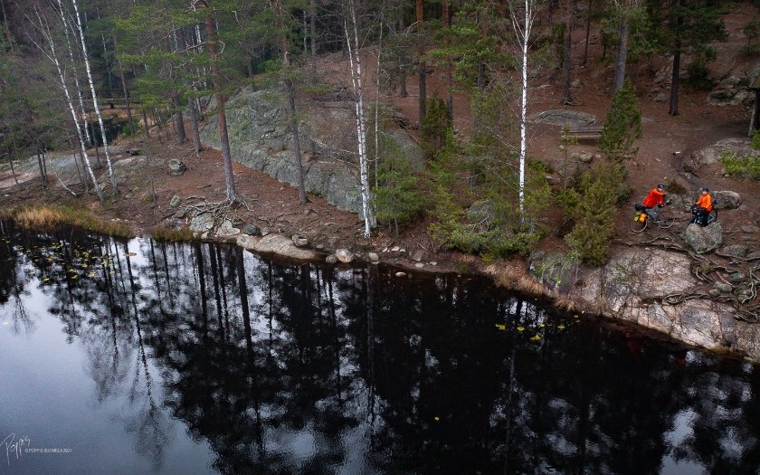 Two cyclists standing next to a lake in Nuuksio National Park