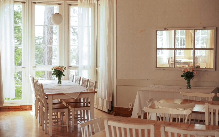 Sisäkuvaa kodikkaasta ja kauniista Villa Frosteruksesta näyttäen suuret ikkunat ja pöytiä.