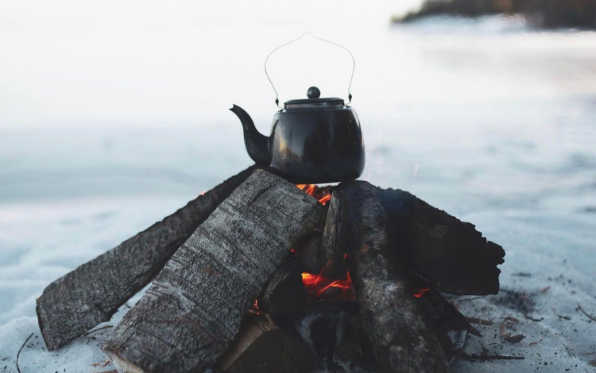 Frozen land with wood campfire and kettle on top