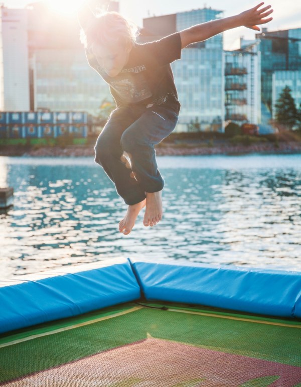 Child jumping on trampoline on the sea
