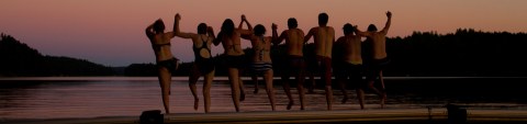 Group jumping to the lake during midnight sun
