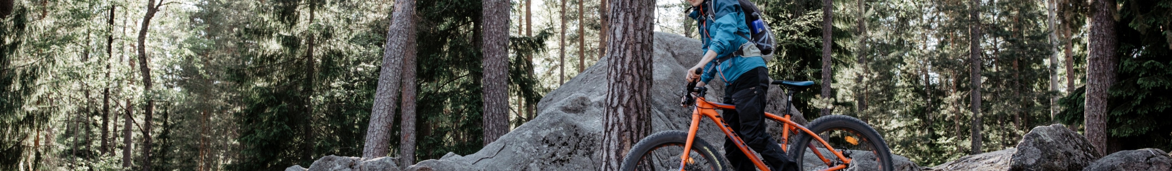 Mies pyöräilemässä metsässä maastopyörällä.