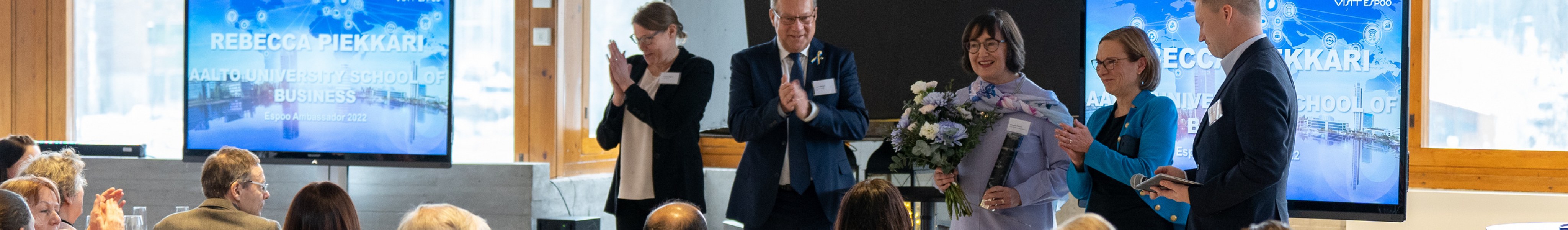 Professor Piekkari receiving the Espoo Ambassador award in front of the audience.