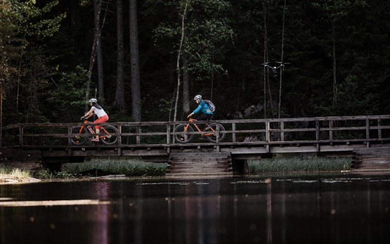 People cycling over the bridge in forest