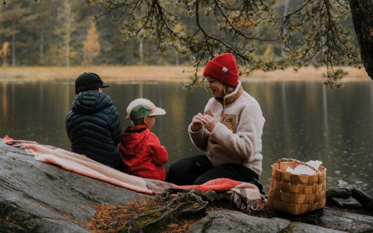 Woman with children having picnic by lake