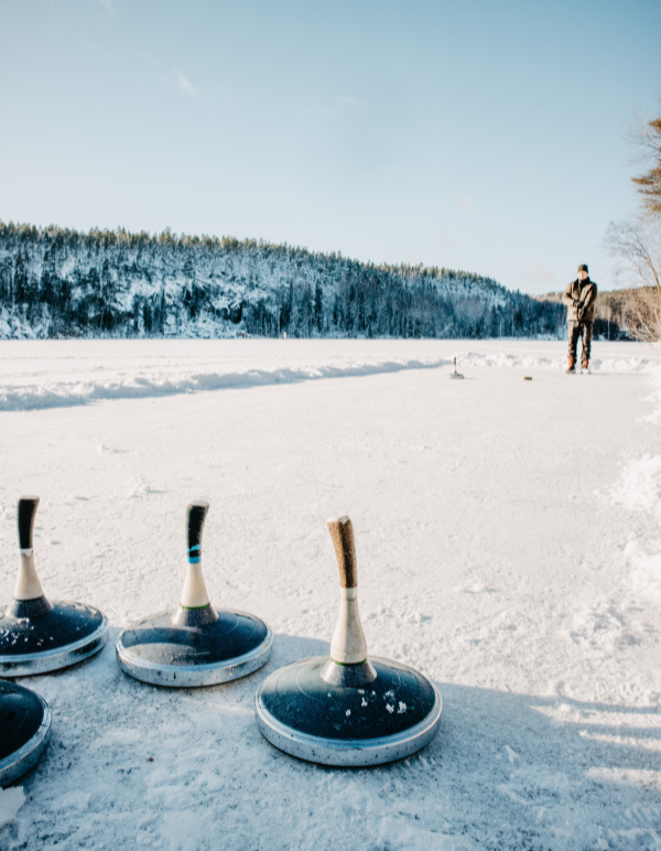 Ice curling with man in distance and game's tools on frozen lake